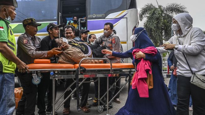 Petugas kepolisian bersama pemudik membantu membaringkan jenazah seorang penumpang bus Sinar Jaya yang meninggal dunia di kawasan Simpang Jomin, Karawang, Jawa Barat, Sabtu (30/4/2022).  ANTARA FOTO/Muhammad Adimaja
