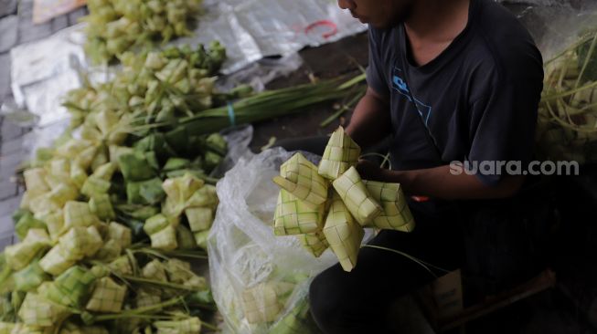 Pedagang menyelesaikan pembuatan kulit ketupat di Pasar Palmerah, Jakarta, Sabtu (30/4/2022). [Suara.com/Angga Budhiyanto]