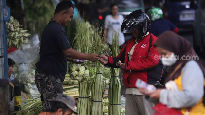 Pedagang kulit ketupat melayani pembeli di Pasar Palmerah, Jakarta, Sabtu (30/4/2022). [Suara.com/Angga Budhiyanto]