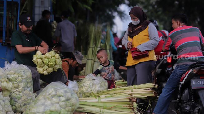 Pedagang kulit ketupat melayani pembeli di Pasar Palmerah, Jakarta, Sabtu (30/4/2022). [Suara.com/Angga Budhiyanto]