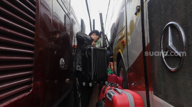 Penumpang memasukkan barang bawaan ke dalam bagasi bus di Terminal Kampung Rambutan, Jakarta, Sabtu (30/4/2022). [Suara.com/Angga Budhiyanto]