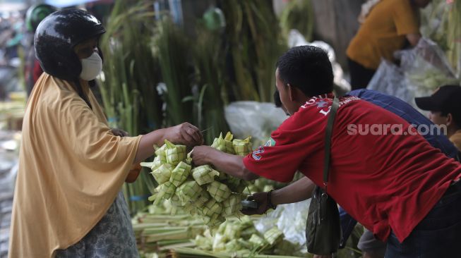 Pedagang kulit ketupat melayani pembeli di Pasar Palmerah, Jakarta, Sabtu (30/4/2022). [Suara.com/Angga Budhiyanto]