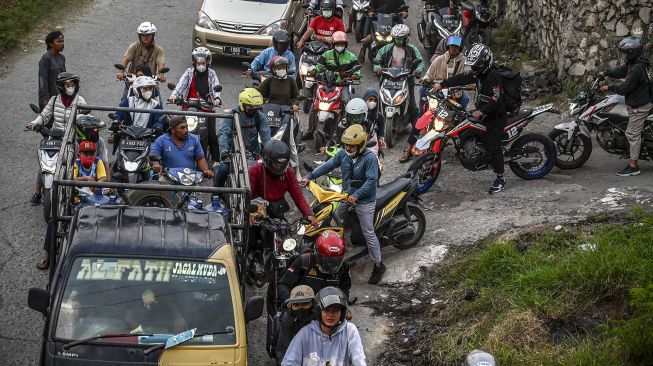 Pengendara sepeda motor melintas di jalur alternatif di Karawang, Jawa Barat, Jumat (29/4/2022).  ANTARA FOTO/Muhammad Adimaja
