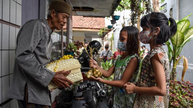 Dua orang anak dari umat kristiani memberikan paket ketupat Lebaran kapada warga umat Islam di Kampung Kerukunan, Lebak, Kabupaten Ciamis, Jawa Barat, Sabtu (30/4/2022). [ANTARA FOTO/Adeng Bustomi/hp]
