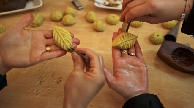 Wanita Palestina membuat kue tradisional Maamoul yang berisi kurma dan kacang-kacangan untuk persiapan hari raya Idul Fitri di kota Hebron, Palestina, Kamis (28/4/2022). [HAZEM BADER / AFP]