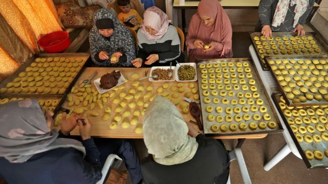 Wanita Palestina membuat kue tradisional Maamoul yang berisi kurma dan kacang-kacangan untuk persiapan hari raya Idul Fitri di kota Hebron, Palestina, Kamis (28/4/2022). [HAZEM BADER / AFP]