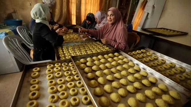 Wanita Palestina membuat kue tradisional Maamoul yang berisi kurma dan kacang-kacangan untuk persiapan hari raya Idul Fitri di kota Hebron, Palestina, Kamis (28/4/2022). [HAZEM BADER / AFP]