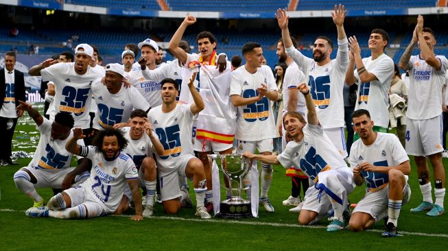 Para pemain Real Madrid berfoto dengan Piala Liga Spanyol pada akhir pertandingan sepak bola Liga Spanyol antara Real Madrid dan Espanyol di Stadion Santiago Bernabeu, Madrid, Spanyol, Sabtu (30/4/2022). [Gabriel BOUYS / AFP]