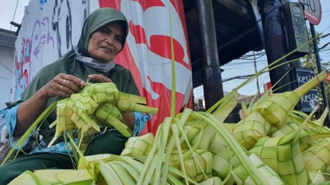 Penjual bungkus ketupat di Jalan Affandi, Mrican, Caturtunggal, Depok, Kabupaten Sleman, Minggu (1/5/2022). [Hiskia Andika Weadcaksana / SuaraJogja.id]