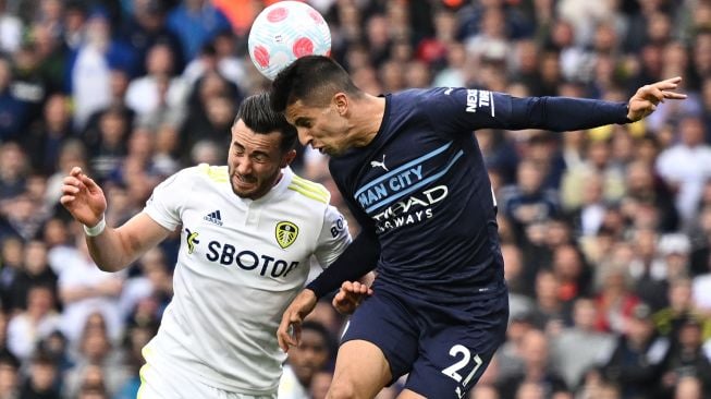 Gelandang Leeds United Jack Harrison (kiri) bersaing dengan bek Manchester City Joao Cancelo (kanan) saat pertandingan sepak bola Liga Premier Inggris antara Leeds United dan Manchester City di Stadion Elland Road, Leeds, Inggris, Sabtu (30/4/2022). [Oli SCARFF / AFP]