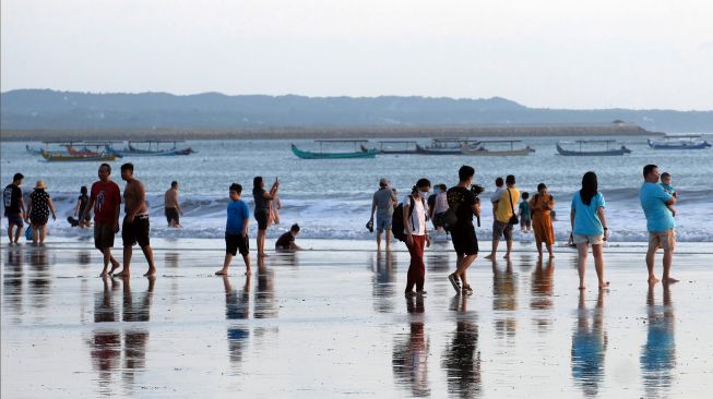 Wisatawan menikmati liburan Hari Raya Idul Fitri 1443 H di Pantai Kuta, Badung, Bali, Senin (2/5/2022). [ANTARA FOTO/Nyoman Hendra Wibowo/nym]