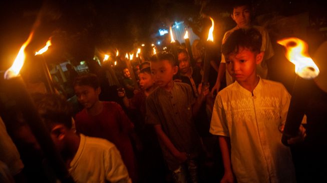 Anak mengikuti pawai obor di Rangkasbitung, Lebak, Banten, Minggu (1/5/2022). [ANTARA FOTO/Muhammad Bagus Khoirunas/nz]