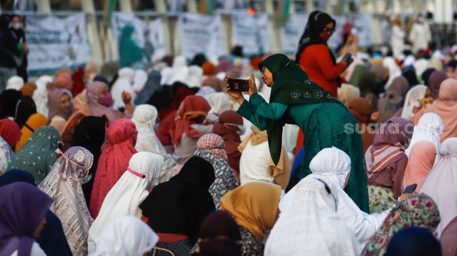 Seorang warga berswafoto sebelum menunaikan ibadah Shalat Idul Fitri 1 Syawal 1443 Hijriah di Jakarta International Stadium (JIS), Tanjung Priok, Jakarta Utara, Senin (2/5/2022). [Suara.com/Alfian Winanto]