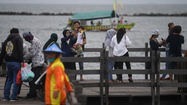 Pengunjung berswafoto di kawasan Pantai Ancol, Taman Impian Jaya Ancol, Jakarta, Selasa (3/5/2022). ANTARA FOTO/Akbar Nugroho Gumay
