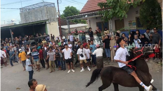 Salah satu penunggang kuda saat melintas di depan masyarakat yang menonton pawai berkuda di Desa Jantuk, Sukamulia, Lombok Timur. [Foto : Suara.com/Toni Hermawan] 