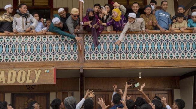 Sejumlah warga berebut uang yang dibagikan pada tradisi Lebaran Arab atau Iwwadh di Palu, Sulawesi Tengah, Selasa (3/5/2022).  ANTARA FOTO/Basri Marzuki
