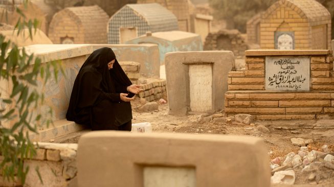 Warga muslim Irak mengunjungi makam kerabat mereka saat badai pasir pada hari pertama Idul Fitri di pemakaman Hassan al-Basri di Distrik Zubayr, Basra, Irak, Senin (2/5/2022). [Hussein Faleh / AFP]