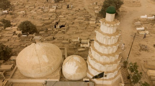 Foto udara menunjukkan warga muslim Irak mengunjungi makam kerabat mereka saat badai pasir pada hari pertama Idul Fitri di pemakaman Hassan al-Basri di Distrik Zubayr, Basra, Irak, Senin (2/5/2022). [Hussein Faleh / AFP]
