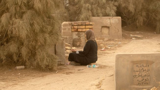 Warga muslim Irak mengunjungi makam kerabat mereka saat badai pasir pada hari pertama Idul Fitri di pemakaman Hassan al-Basri di Distrik Zubayr, Basra, Irak, Senin (2/5/2022). [Hussein Faleh / AFP]