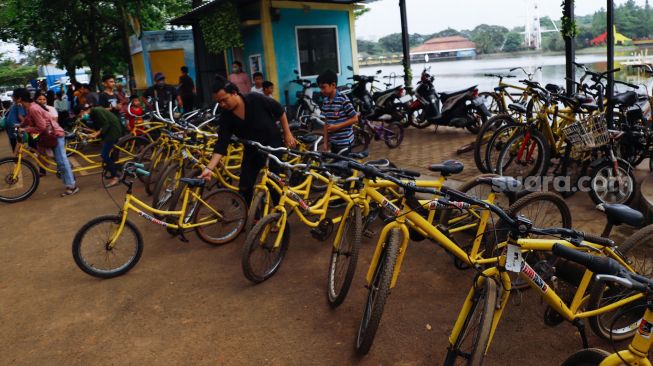 Pengunjung menyewa sepeda untuk berkeliling di Taman Mini Indonesia Indah, Jakarta Timur, Rabu (4/5/2022). [Suara.com/Alfian Winanto]