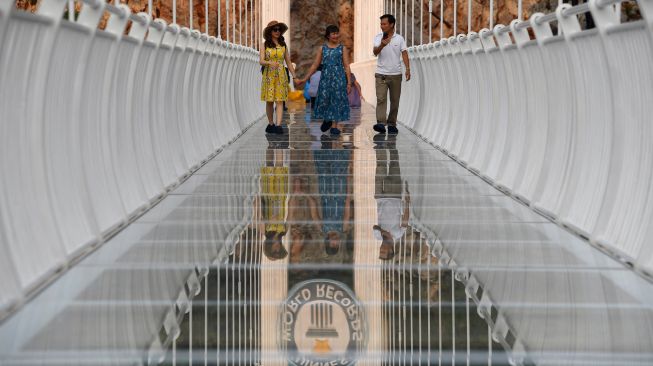 Pengunjung berjalan di jembatan kaca Bach Long di distrik Moc Chau, Son La, Vietnam, Jumat (29/4/2022). [Nhac NGUYEN / AFP]