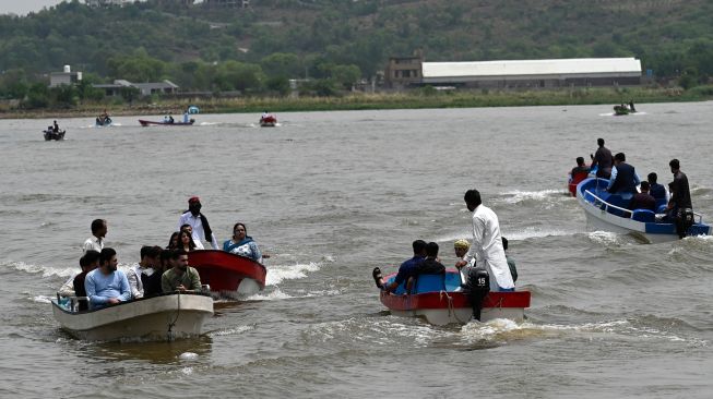 Warga Muslim menaiki perahu di danau saat hari raya Idul Fitri di Islamabad, Pakistan, Selasa (3/5/2022). [Aamir QURESHI / AFP]