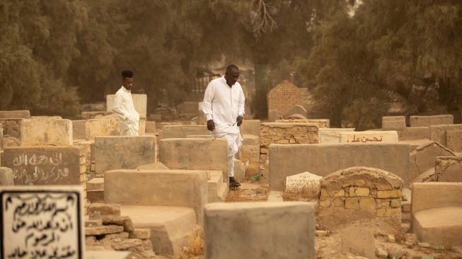 Warga muslim Irak mengunjungi makam kerabat mereka saat badai pasir pada hari pertama Idul Fitri di pemakaman Hassan al-Basri di Distrik Zubayr, Basra, Irak, Senin (2/5/2022). [Hussein Faleh / AFP]