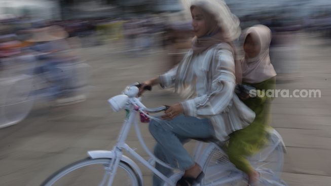 Warga menaiki sepeda saat berwisata di Taman Fatahillah, Kota Tua, Jakarta, Kamis (5/5/2022). [Suara.com/Angga Budhiyanto]