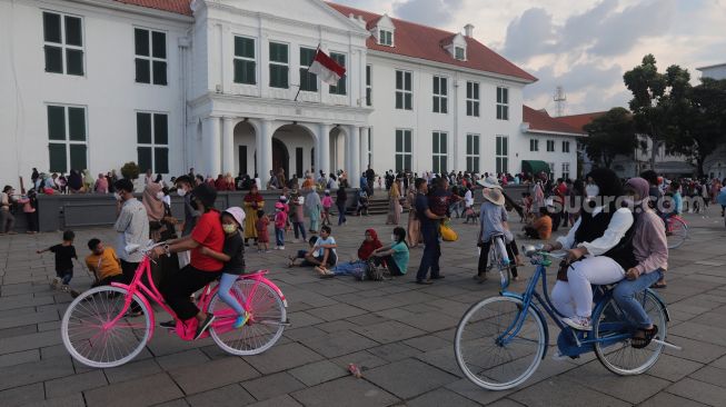Warga menaiki sepeda saat berwisata di Taman Fatahillah, Kota Tua, Jakarta, Kamis (5/5/2022). [Suara.com/Angga Budhiyanto]
