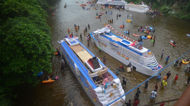 Sejumlah warga mendorong kajang (perahu yang dihias serupa kapal pesiar) saat digelarnya tradisi Bakajang di Sungai Batang Mahek, Nagari Gunuang Malintang, Kabupaten Limapuluhkota, Sumatera Barat, Kamis (5/5/2022). [ANTARA FOTO/Iggoy el Fitra]