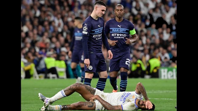 Reaksi gelandang Manchester City Phil Foden (Atas) ketika bek Real Madrid Eder Militao berbaring di lapangan saat pertandingan sepak bola leg kedua semifinal UEFA Liga Champions antara Real Madrid dan Manchester City di stadion Santiago Bernabeu, Madrid, Spanyol, Rabu (4/5/2022). [JAVIER SORIANO / AFP]