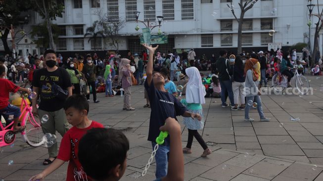 Warga bermain gelembung sabun saat berwisata di Taman Fatahillah, Kota Tua, Jakarta, Kamis (5/5/2022). [Suara.com/Angga Budhiyanto]