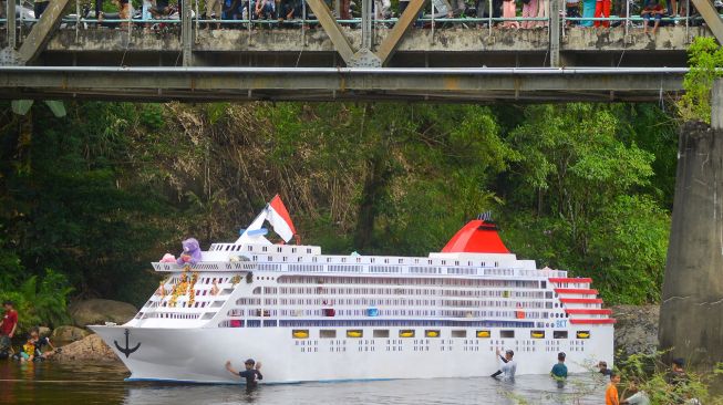 Sejumlah warga mendorong kajang (perahu yang dihias serupa kapal pesiar) saat digelarnya tradisi Bakajang di Sungai Batang Mahek, Nagari Gunuang Malintang, Kabupaten Limapuluhkota, Sumatera Barat, Kamis (5/5/2022). [ANTARA FOTO/Iggoy el Fitra]