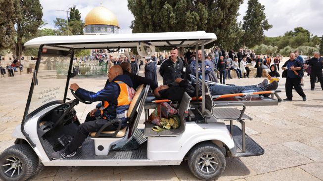 Anggota Bulan Sabit Merah Palestina mengevakuasi seorang pria selama bentrokan dengan pasukan keamanan Israel di kompleks Masjid Al-Aqsa di Yerusalem, pada (5/5/2022). [AHMAD GHARABLI / AFP]