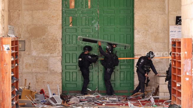 Polisi Israel mengamankan pintu Masjid Al-Aqsha selama bentrokan dengan warga Palestina di Yerusalem, pada (5/5/2022). [AHMAD GHARABLI / AFP]