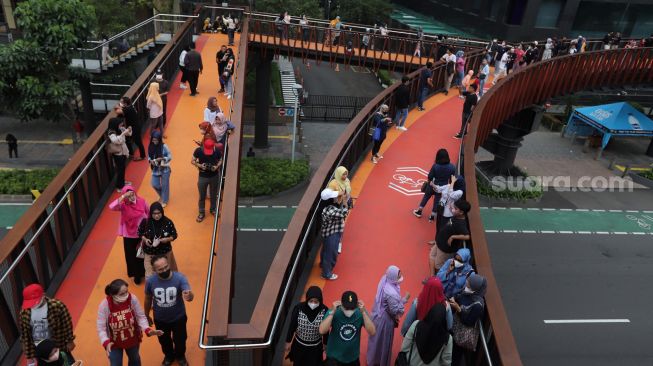 Warga menikmati suasana di Jembatan Penyeberangan Orang (JPO) Pinisi Karet-Sudirman, Jakarta, Sabtu (7/5/2022). [Suara.com/Angga Budhiyanto]