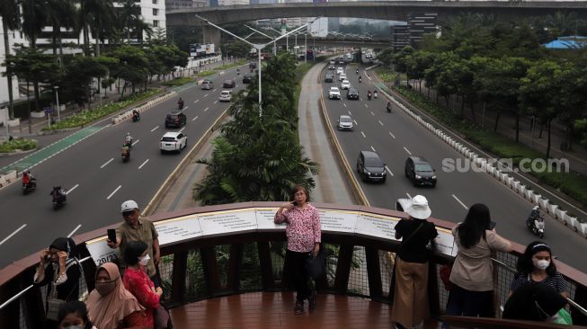 Warga berfoto di Jembatan Penyeberangan Orang (JPO) Pinisi Karet-Sudirman, Jakarta, Sabtu (7/5/2022). [Suara.com/Angga Budhiyanto]