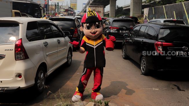 Pengamen badut mencari nafkah saat sejumlah kendaraan terjebak kemacetan di Jalan Raya Kalimalang, Bekasi, Jawa Barat, Sabtu (7/5/2022). [Suara.com/Angga Budhiyanto]