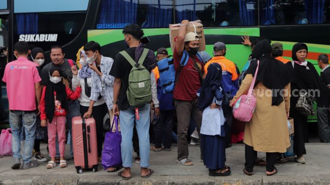 Pemudik membawa barang bawaan setibanya di Terminal Kampung Rambutan, Jakarta, Sabtu (7/5/2022). [Suara.com/Angga Budhiyanto]