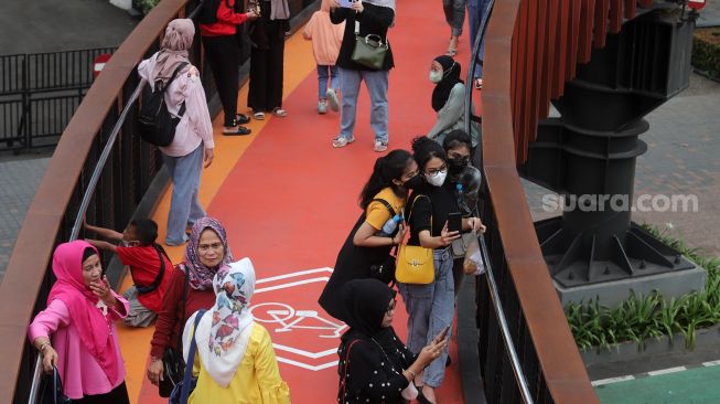 Warga berswafoto di Jembatan Penyeberangan Orang (JPO) Pinisi Karet-Sudirman, Jakarta, Sabtu (7/5/2022). [Suara.com/Angga Budhiyanto]