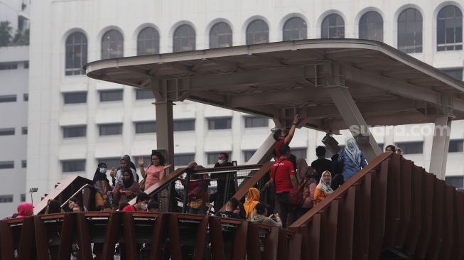 Warga menikmati suasana di Jembatan Penyeberangan Orang (JPO) Pinisi Karet-Sudirman, Jakarta, Sabtu (7/5/2022). [Suara.com/Angga Budhiyanto]