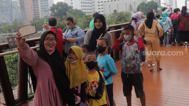 Warga berswafoto di Jembatan Penyeberangan Orang (JPO) Pinisi Karet-Sudirman, Jakarta, Sabtu (7/5/2022). [Suara.com/Angga Budhiyanto]