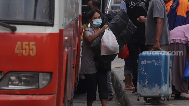 Pemudik membawa barang bawaan setibanya di Terminal Kampung Rambutan, Jakarta, Sabtu (7/5/2022). [Suara.com/Angga Budhiyanto]