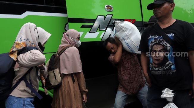 Pemudik menurunkan barang bawaan dari bagasi bus setibanya di Terminal Kampung Rambutan, Jakarta, Sabtu (7/5/2022). [Suara.com/Angga Budhiyanto]