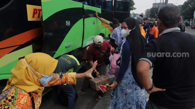 Pemudik menurunkan barang bawaan dari bagasi bus setibanya di Terminal Kampung Rambutan, Jakarta, Sabtu (7/5/2022). [Suara.com/Angga Budhiyanto]