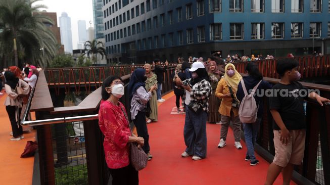 Warga menikmati suasana di Jembatan Penyeberangan Orang (JPO) Pinisi Karet-Sudirman, Jakarta, Sabtu (7/5/2022). [Suara.com/Angga Budhiyanto]