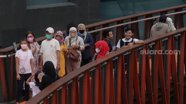 Warga berfoto di Jembatan Penyeberangan Orang (JPO) Pinisi Karet-Sudirman, Jakarta, Sabtu (7/5/2022). [Suara.com/Angga Budhiyanto]