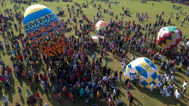 Foto udara sejumlah warga menerbangkan balon udara yang ditambatkan di tanah saat "Balloon Attraction Pekalongan 2022" di Lapangan Mataram, Kota Pekalongan, Jawa Tengah, Minggu (8/5/2022). [ANTARA FOTO/Harviyan Perdana Putra/aww]