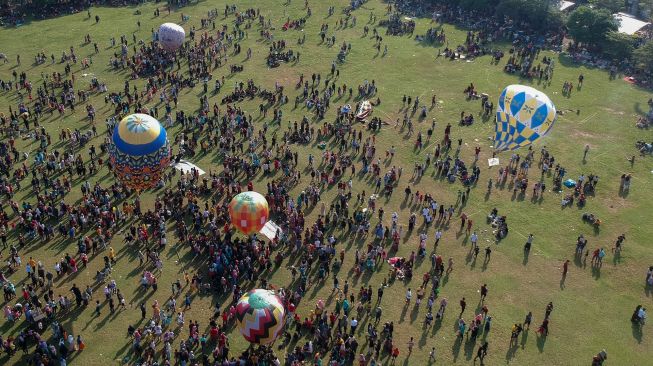 Foto udara sejumlah warga menerbangkan balon udara yang ditambatkan di tanah saat "Balloon Attraction Pekalongan 2022" di Lapangan Mataram, Kota Pekalongan, Jawa Tengah, Minggu (8/5/2022). [ANTARA FOTO/Harviyan Perdana Putra/aww]