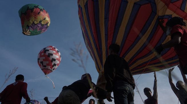 Sejumlah warga menerbangkan balon udara yang ditambatkan di tanah saat "Balloon Attraction Pekalongan 2022" di Lapangan Mataram, Kota Pekalongan, Jawa Tengah, Minggu (8/5/2022). [ANTARA FOTO/Harviyan Perdana Putra/aww]